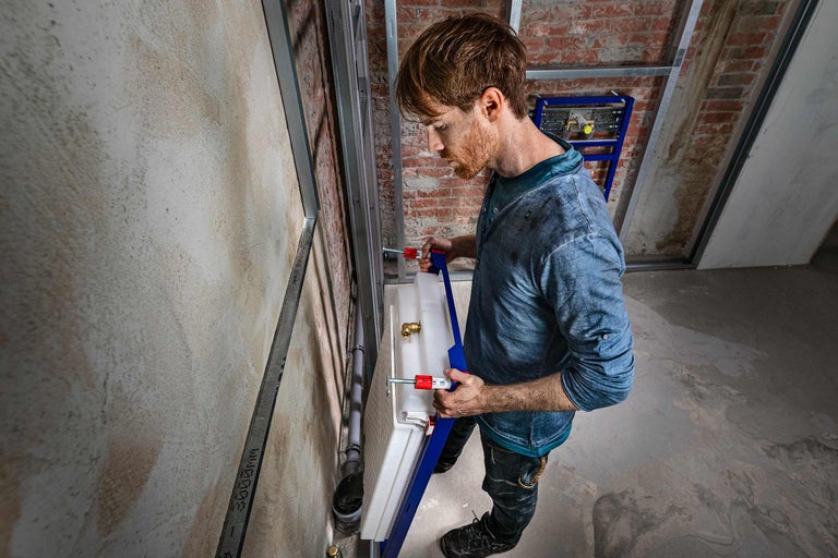 Installateur monteert inbouwreservoir in de badkamer.