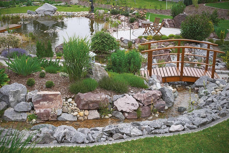 Tuinvijver met houten brug, stenen en beplanting