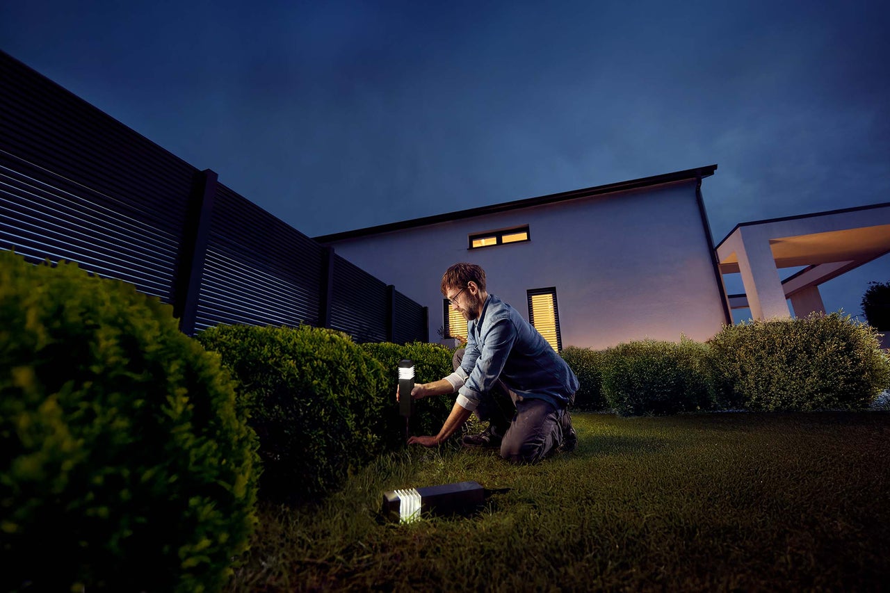 Man installeert tuinverlichting in de tuin.