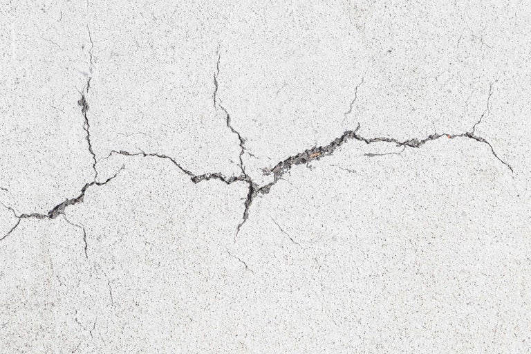 Close-up van een betonnen muur met scheuren