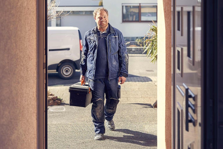 Ambachtsman met gereedschapskist voor een gebouw