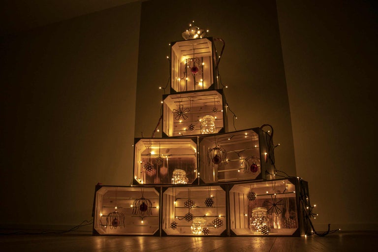 Decoratieve kerstboom gemaakt van houten kisten met lichtjes en ornamenten