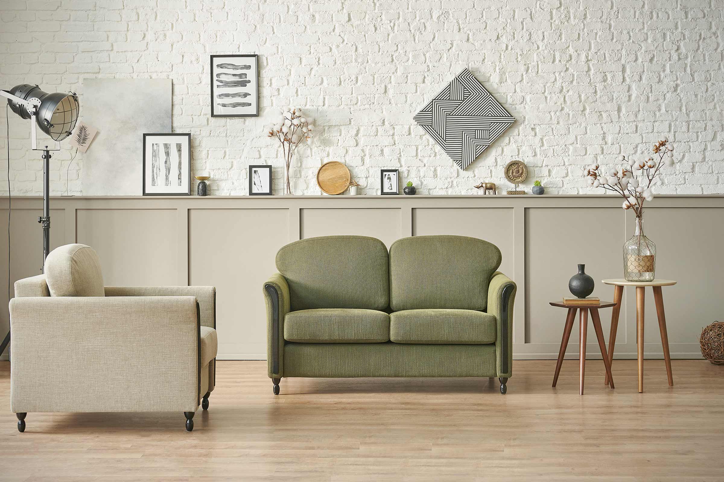 Woonkamer met groene bank, fauteuil en decoratie tegen een witte bakstenen muur