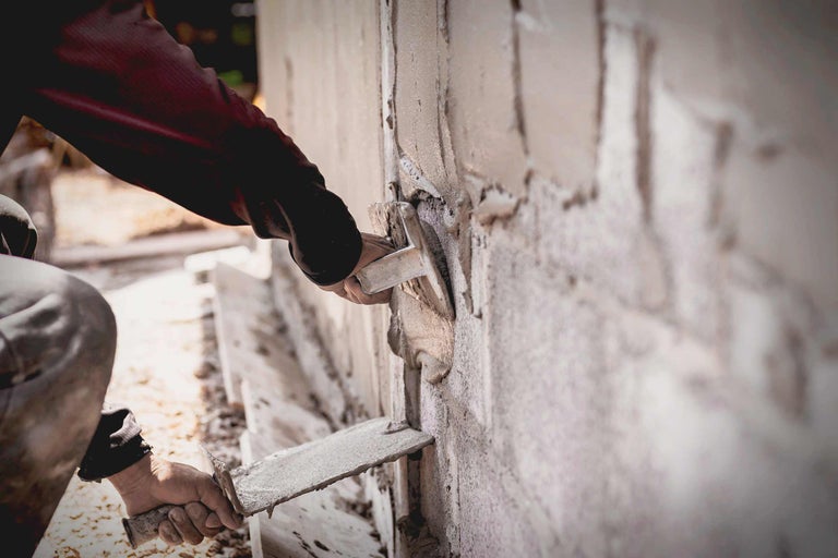 Ambachtsman pleistert een muur met een troffel