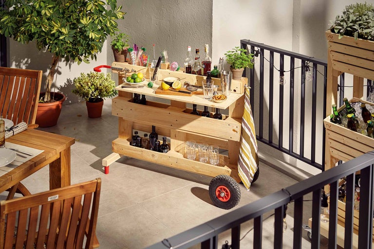 Foto van een houten bar op een balkon, gevuld met drankjes en glazen.