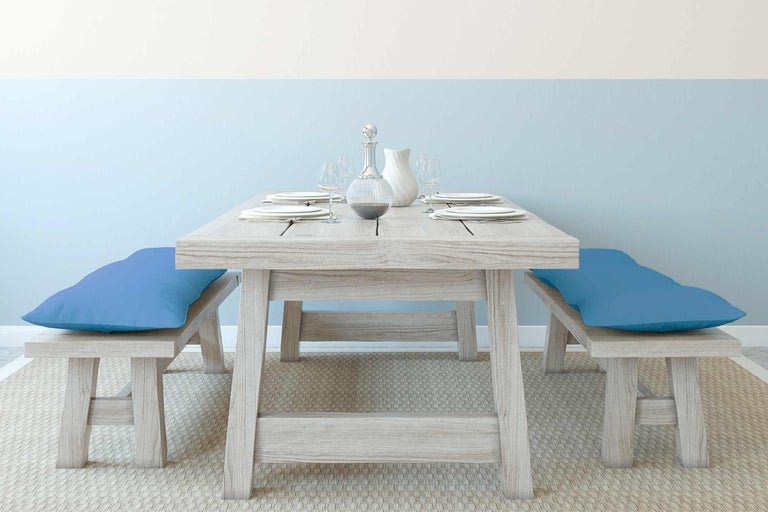 Houten eettafelset met banken en blauwe kussens op een tapijt