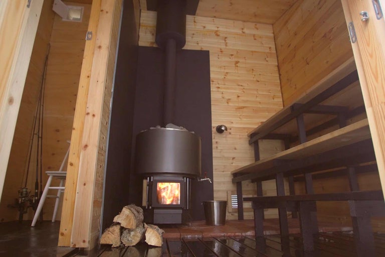 Houten sauna met houtkachel en saunabanken