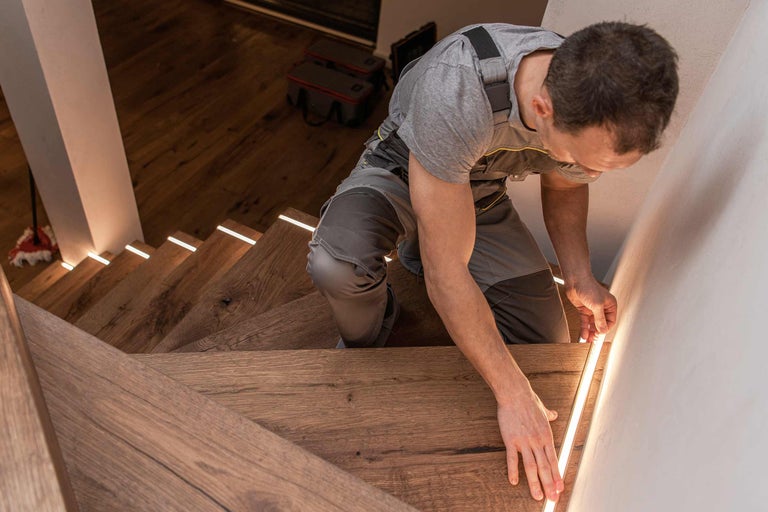 Vakman installeert ledverlichting op houten trap voor Hornbach