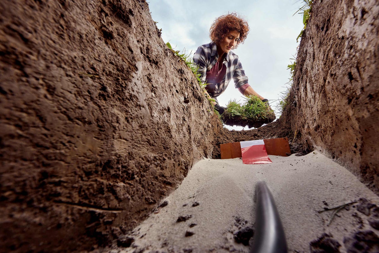 Vrouw legt graszoden in een voorbereide sleuf voor drainage