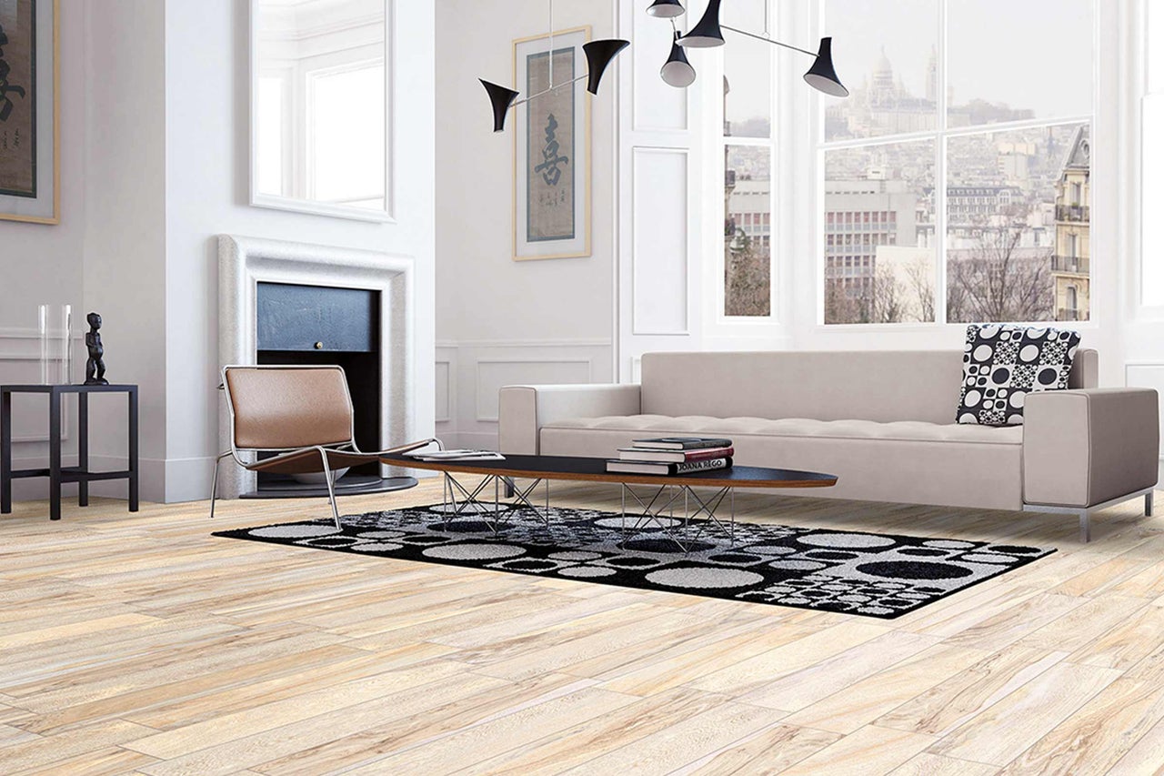 Lichte woonkamer met bank, fauteuil, tapijt en houten vloer