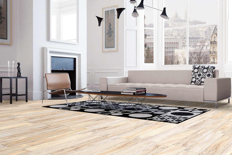 Lichte woonkamer met bank, fauteuil, tapijt en houten vloer