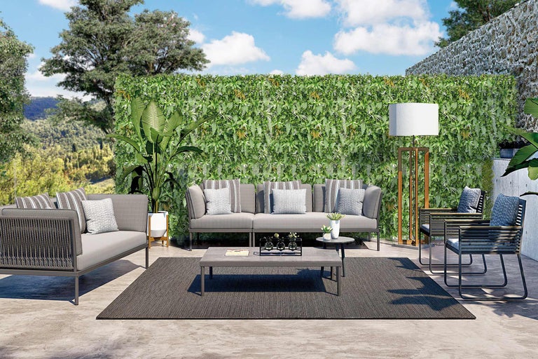 Terras met bank, fauteuils, tafel, vloerkleed en plantenwand