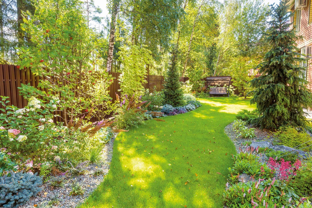 Tuinlandschap met gazon, bloembedden en sierstruiken