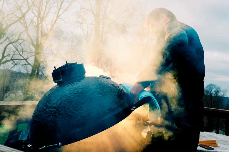 Man reinigt keramische barbecue buiten met grillborstel