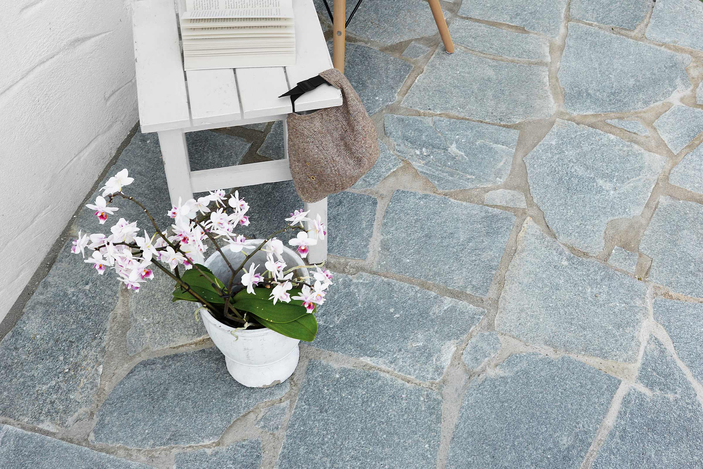 Terras met natuurstenen tegels, versierd met tafel, boeken, tas en potplant