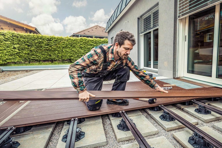 Man legt terrasplanken op een terras met verstelbare poten.