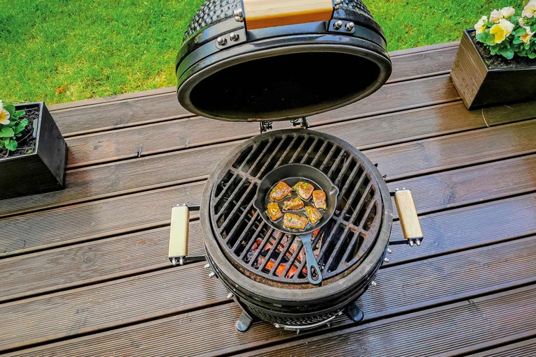 Keramische barbecue met open kap en gegrild voedsel in een pan