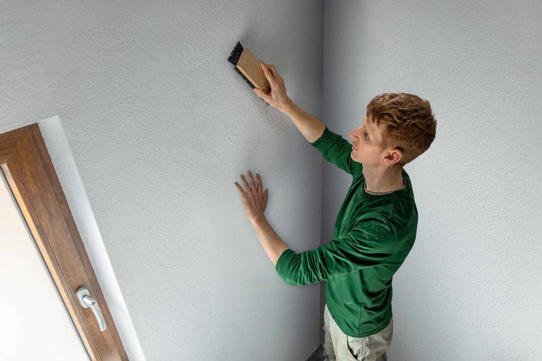 Man structureert muur met borstel