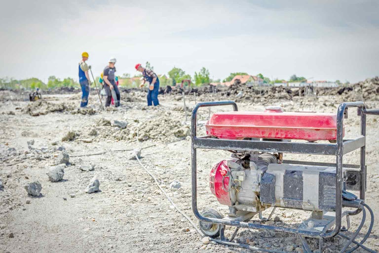 Stroomgenerator op een bouwplaats met bouwvakkers op de achtergrond