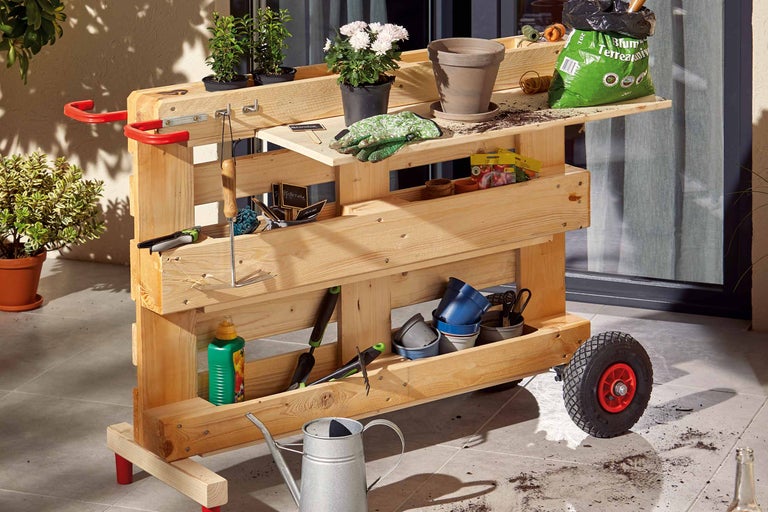 Houten tuinwagen met tuingereedschap, bloemen en potgrond