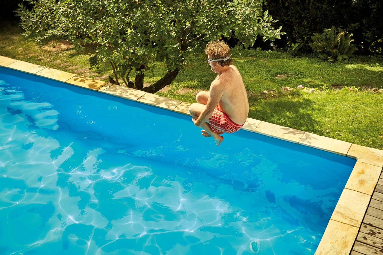 Man springt in het zwembad in de tuin.