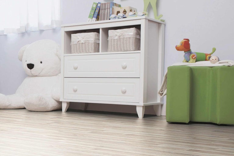 Kinderkamer met witte commode, speelgoed en houten vloer