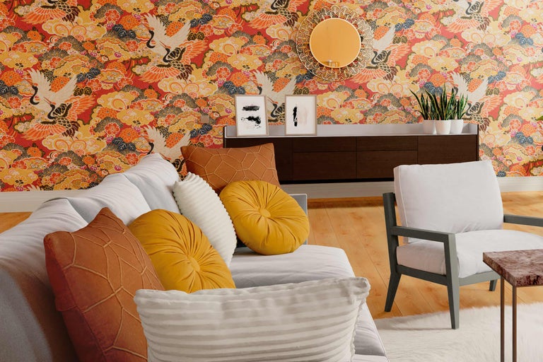 Woonkamer met bank, fauteuil, dressoir, spiegel, schilderijen en behang met kraanvogelmotief.