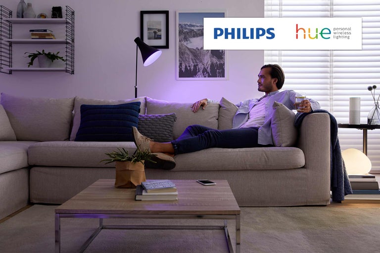 Woonkamer met Philips Hue verlichting en ontspannen man op de bank