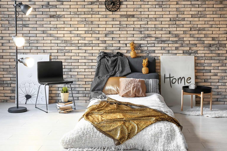 Decoratieve slaapkamer met bed, stoel, vloerlamp en bakstenen muur