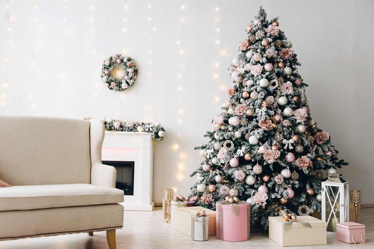 Versierde kerstboom in de woonkamer met fauteuil, open haard en geschenken.
