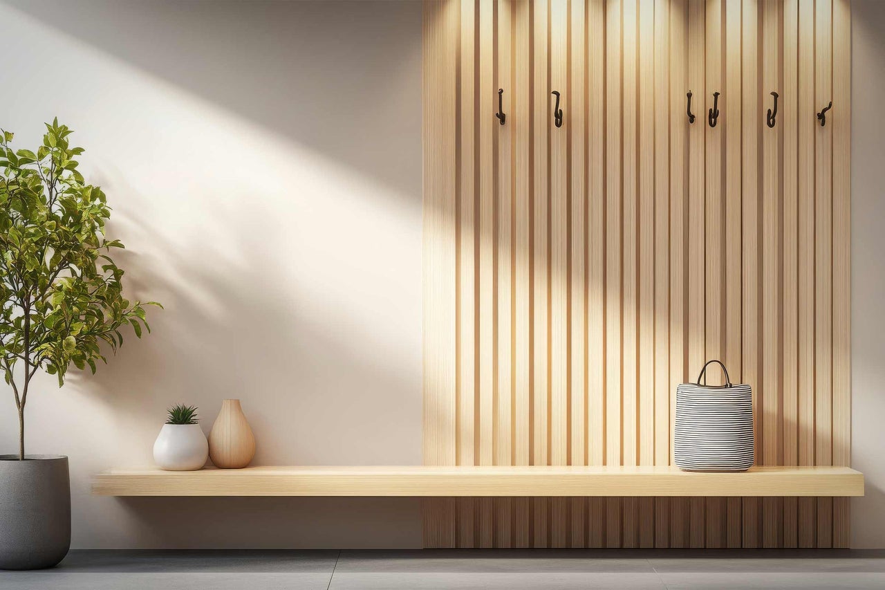 Lichte ruimte met garderobe, houten bank, plant en accessoires