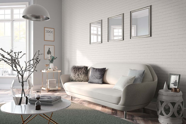 Lichte woonkamer met bank, salontafel, bijzettafel en wanddecoraties voor een bakstenen muur