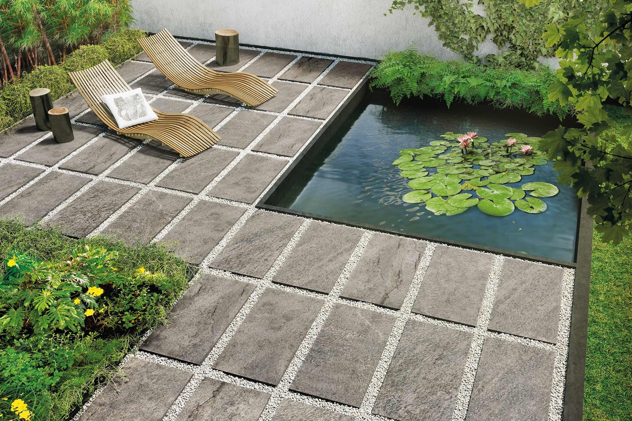 Tuinscene met terrastegels, grindvoegen, vijver, ligstoelen en beplanting
