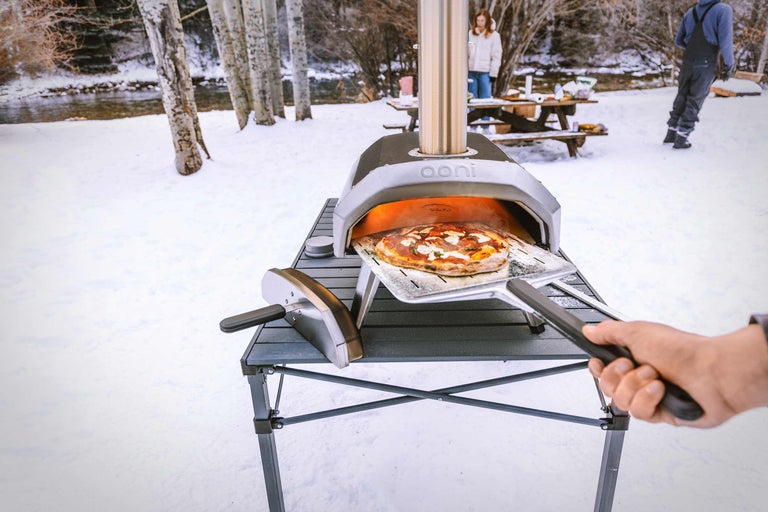 Pizzaoven in de buitenlucht met pizza op pizzaschep