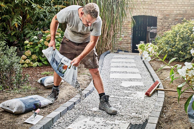 Man stort grindpad in de tuin met decoratief grind uit een zak