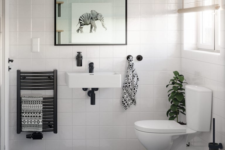 Lichte badkamer met wastafel, toilet, handdoekradiator en decoraties