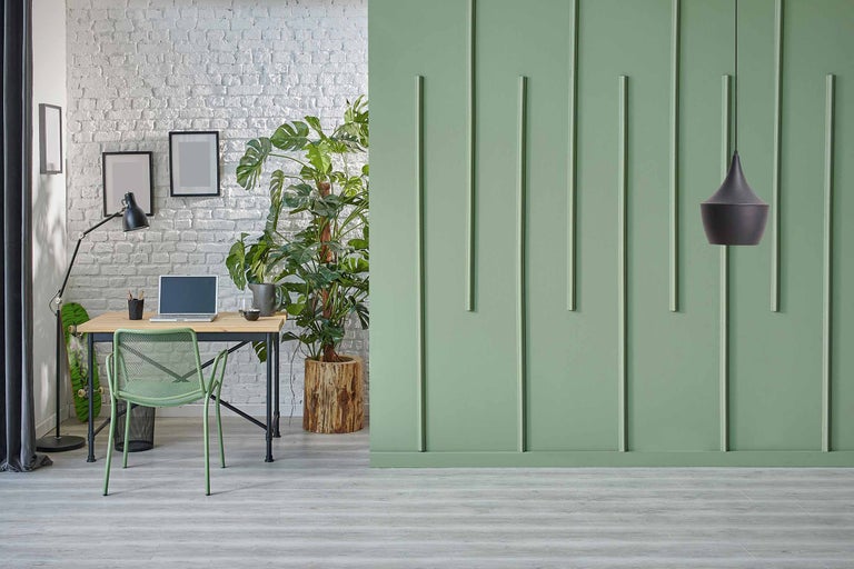Lichte studeerkamer met bureau, stoel en kamerplant voor een groene muur