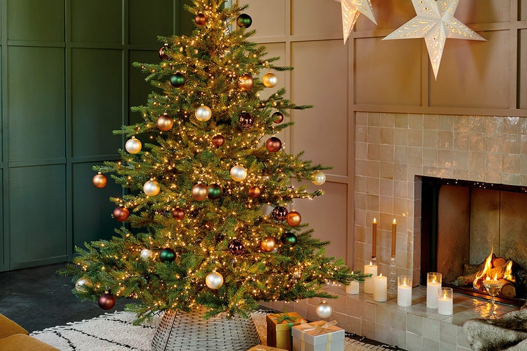 Versierde kerstboom met lichtjes, kerstballen en cadeaus in een woonkamer