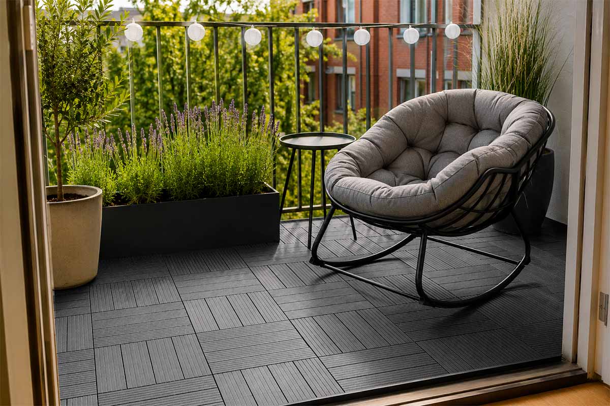 Modern balkon met donkergrijze vlondertegels, grijze schommelstoel met kussen, bijzettafel, lavendel in een plantenbak en lichtsnoer.