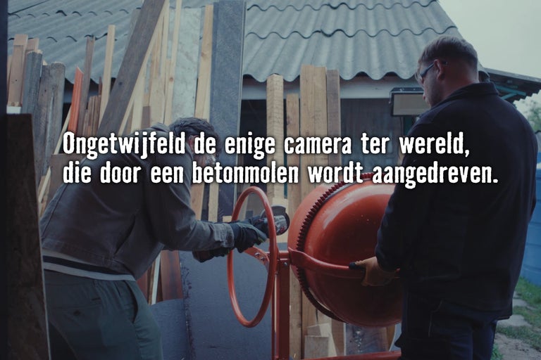 Twee vakmensen werken in een werkplaats met een betonmolen en gereedschap.