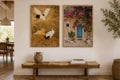 Twee ingelijste wandafbeeldingen boven een houten bank. Motieven van Japanse kraanvogels en een mediterrane deur met bloemen. Lichte kamer.
