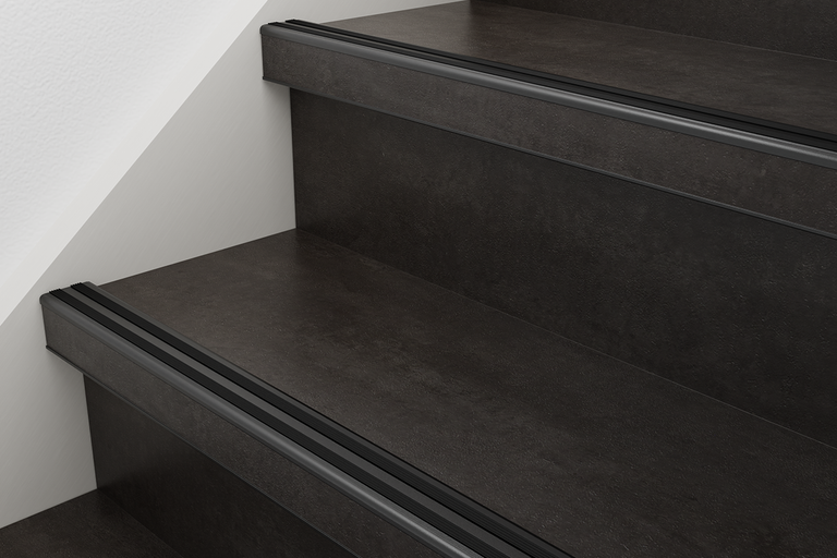 Trapkantprofiel van aluminium met zwarte antislip-inleg op donkere treden.