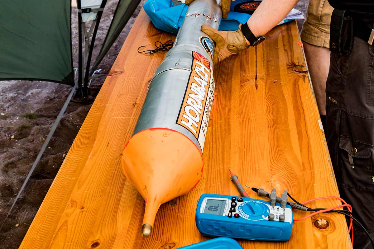 Een raketmodel met Hornbach-logo op een houten tafel met een multimeter