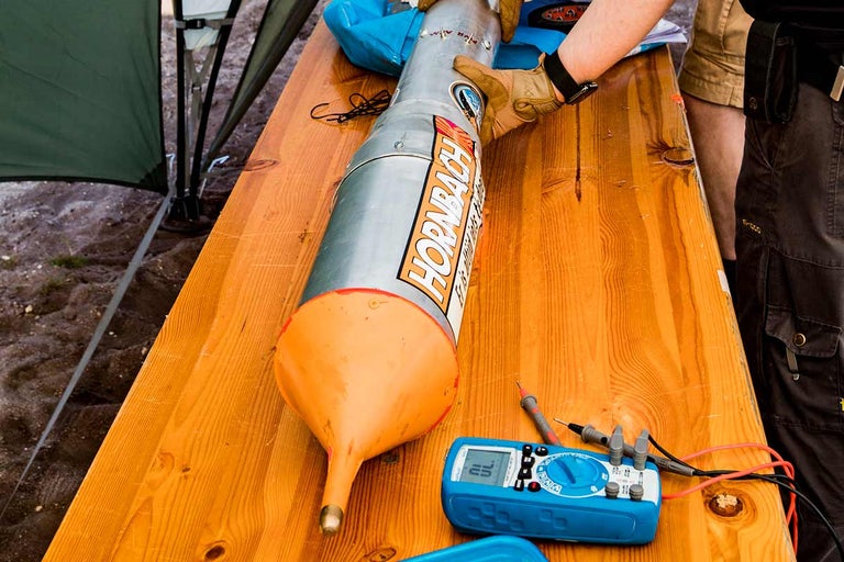 Een raketmodel met Hornbach-logo op een houten tafel met een multimeter