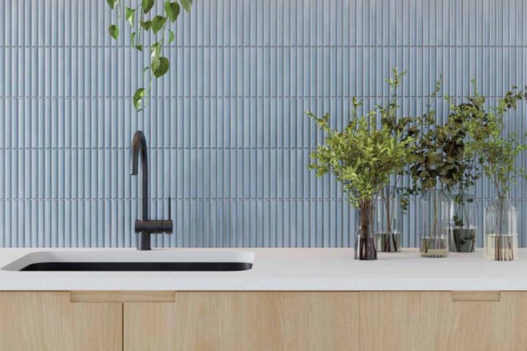 Badkamer met blauwe wandtegels, wastafel en kraan