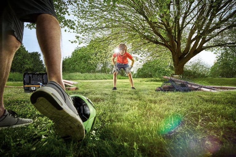 Tuinscene met gazon, gereedschapskist, voetbal en twee personen