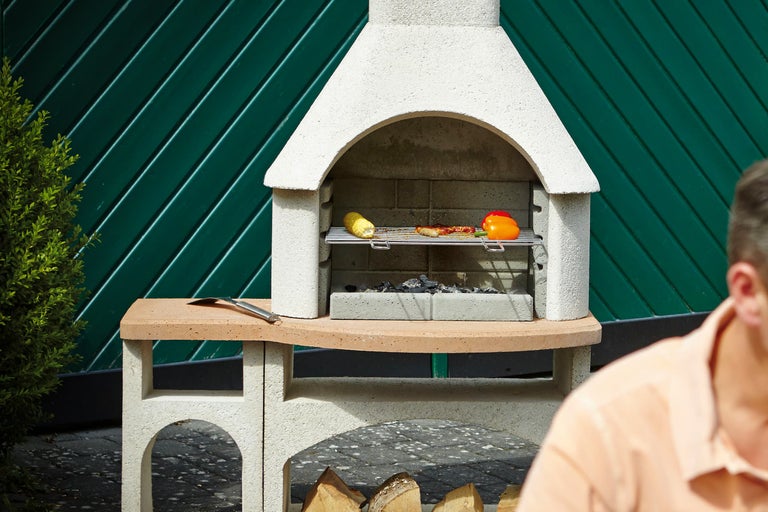 Gemetselde tuingrill met gegrild voedsel en barbecuegereedschap