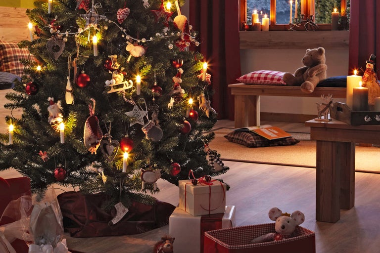 Feestelijk versierde kerstboom in een gezellige woonkamer met cadeaus en decoraties.