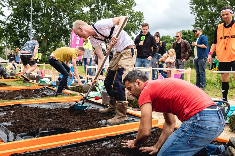 Mensen die deelnemen aan een tuinierwedstrijd vullen verhoogde bedden met aarde.