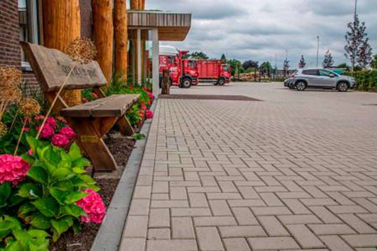 Buitenterrein met straatstenen, zitbank en beplanting
